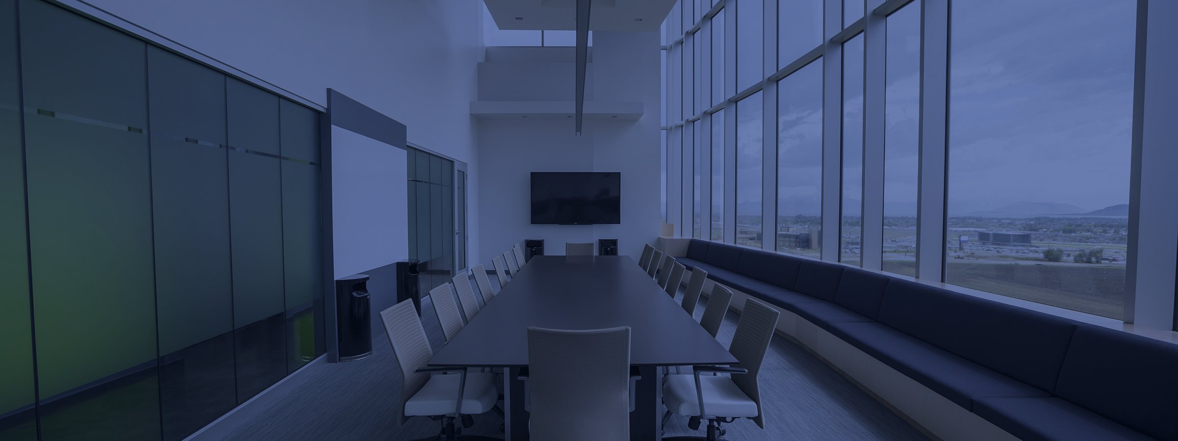 An empty boardroom table along a wall of windows