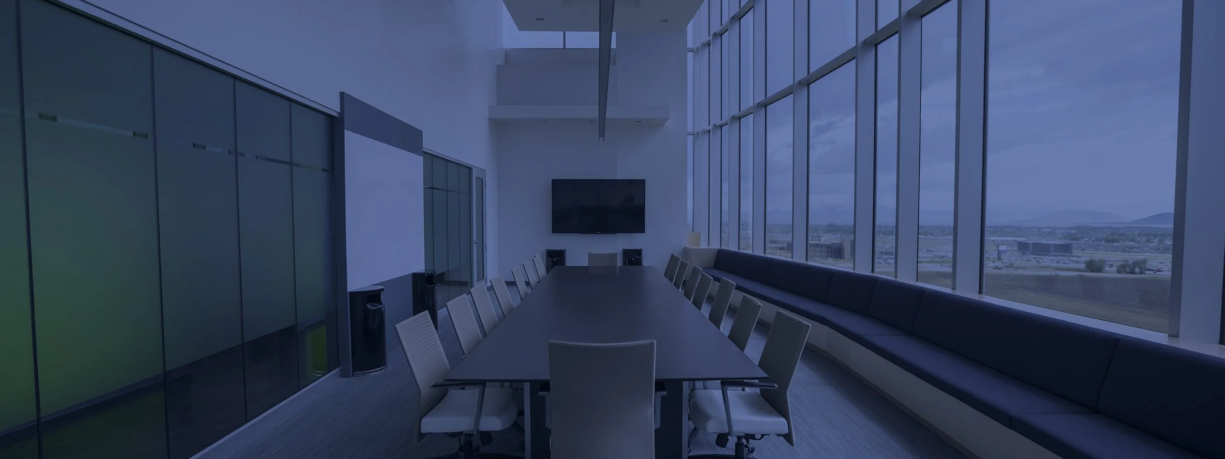 An empty boardroom table along a wall of windows